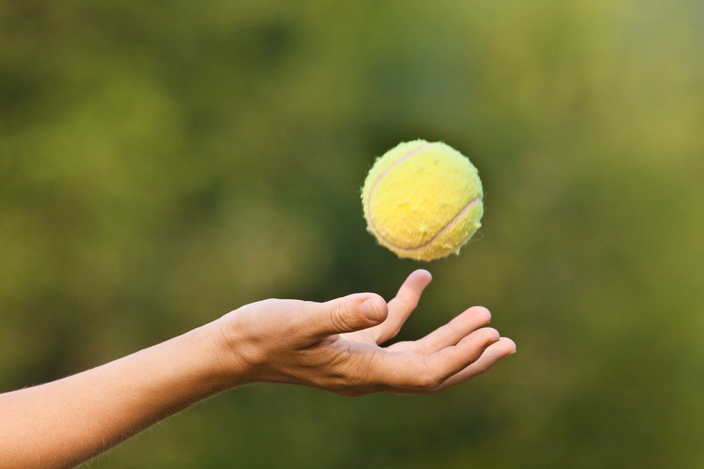 Mano che tossing palla da tennis